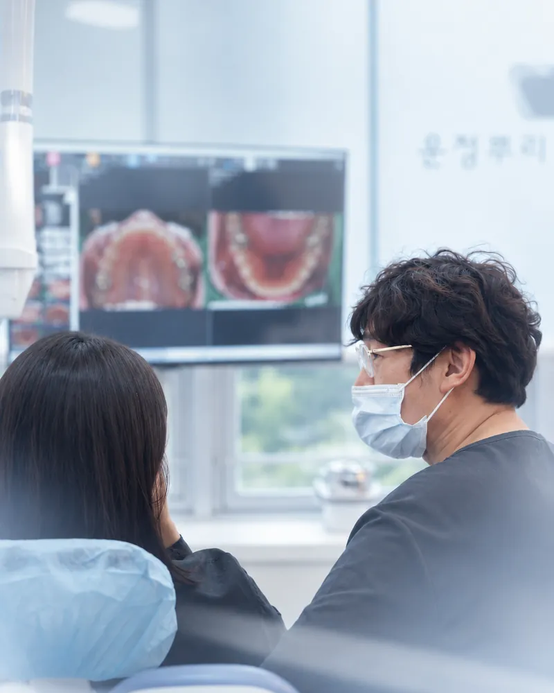 진료 의자의 환자와 함께 모니터의 구강 사진을 보는 원장